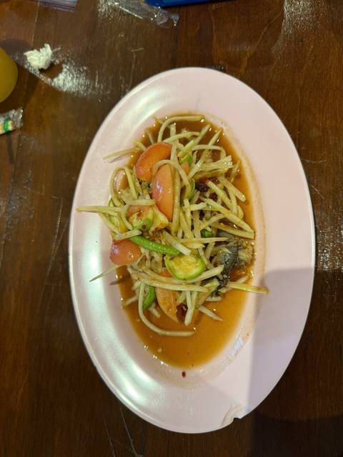       Plate of Thai green papaya salad with tomatoes and long beans dressed in zesty sauce.
  