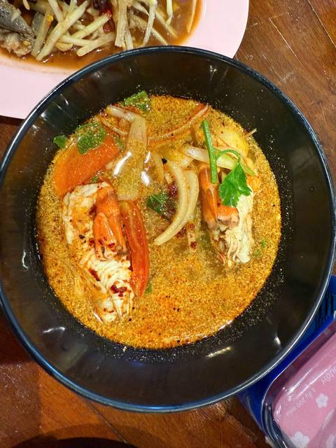       Bowl of spicy Thai tom yum soup featuring prawns and aromatic herbs in rich broth.
  