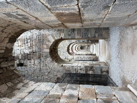       Stone vaulted arcade of ancient Roman ruins with repeating arches
  