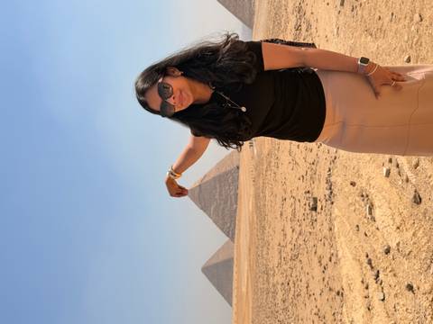       Woman playfully pinching distant pyramid tip in desert landscape
  