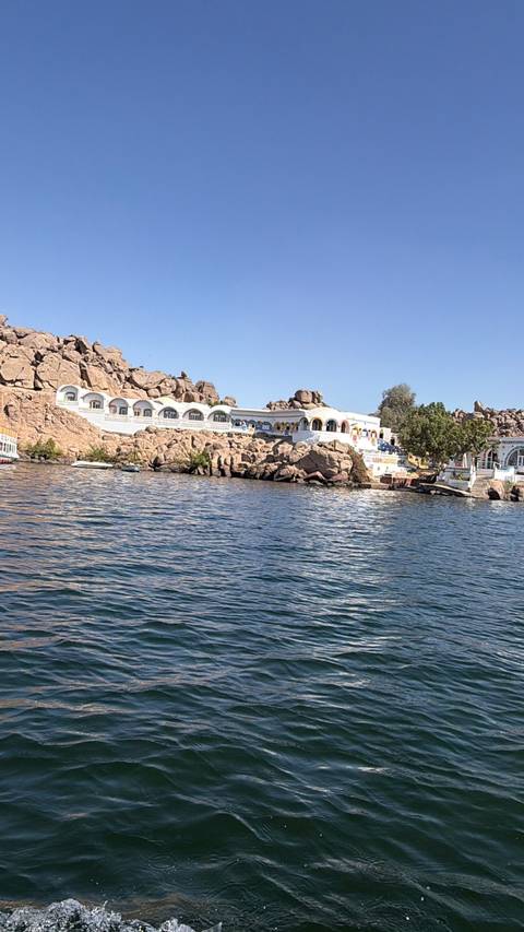       Colorful Nubian riverside village buildings perched on rocky Nile bank
  