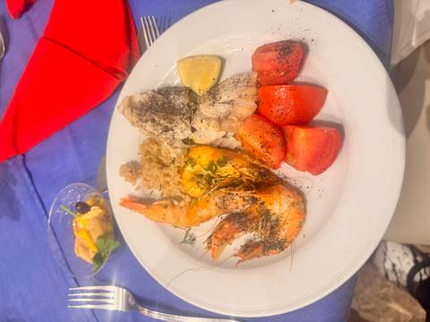       Dinner plate with prawns, fish, rice and tomatoes on restaurant table
  