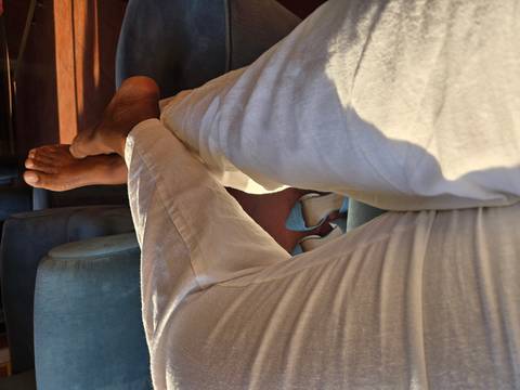       Relaxed perspective of a person’s crossed legs on a sofa with shoes on the floor below.
  