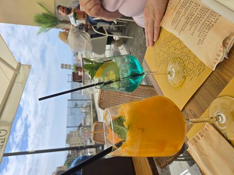       Colorful orange and turquoise cocktails on a seaside terrace with distant coastal view
  