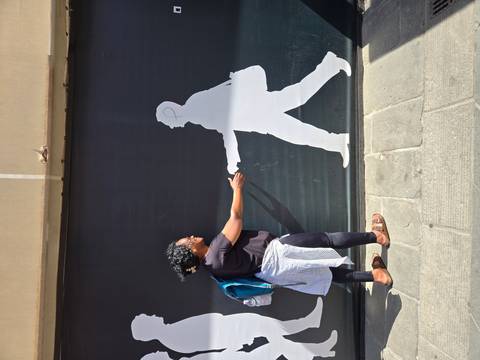       Traveler playfully posing as if shaking hands with a silhouette street art figure
  