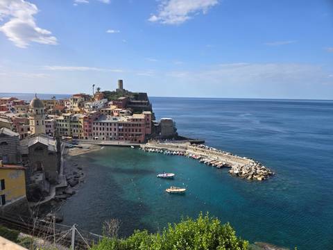       Panoramic view of Vernazza harbor with colorful buildings and boats on deep blue Ligurian Sea
  