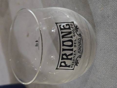       Small glass branded 'Prione Essenza del Golfo' on a table
  