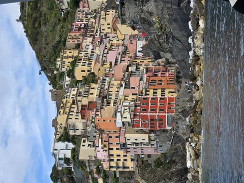       Colorful cliffside houses of Riomaggiore rising above rocky shoreline
  