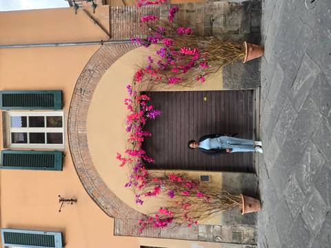       Woman posing in front of a wooden door framed by bright pink bougainvillea
  