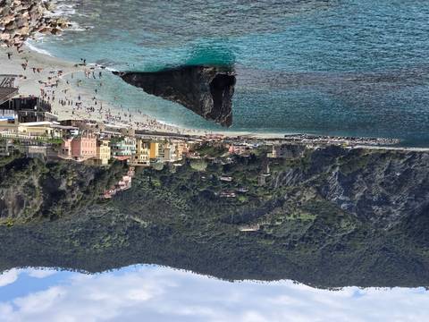       Monterosso al Mare beach with iconic rock formation and turquoise water surrounded by cliffs
  