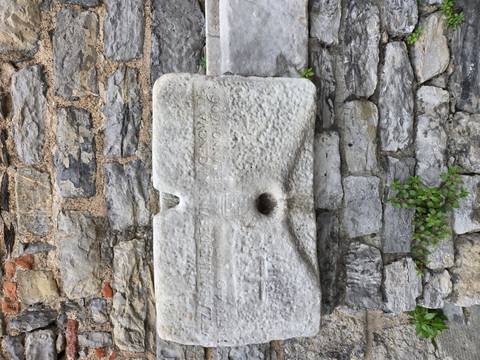       Weathered marble trough inset in a stone wall with faint historic inscription
  