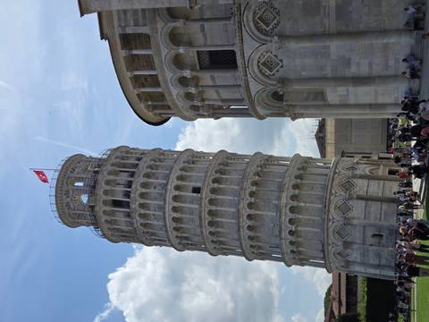       Leaning Tower of Pisa beside Pisa Cathedral under partly cloudy sky with crowds below
  