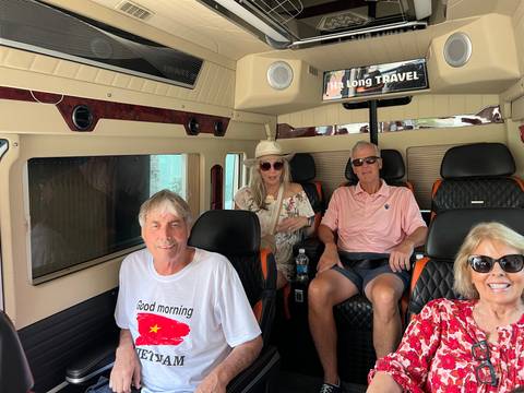       Travelers relax inside a comfortable minibus labeled 'Ha Long Travel' en route to their next destination.
  