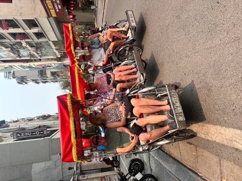       Line of traditional cycle rickshaws with tourists ready to explore busy Hanoi streets under bright sun.
  