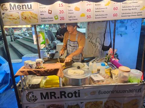       Street-food vendor preparing roti at a brightly lit night stall
  