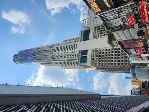       Tall Baiyoke Sky Tower rising above surrounding Bangkok buildings on a sunny day
  