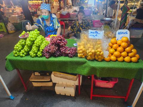       Fruit stall displaying piles of grapes and oranges at a night market
  