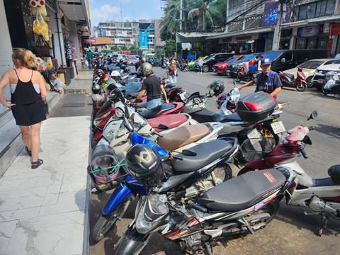       Busy street lined with tightly parked motorbikes and pedestrians
  