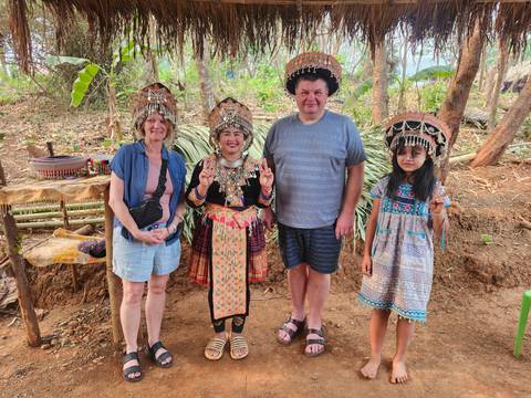       Tourists posing with local hill-tribe hosts wearing traditional ornate headdresses
  