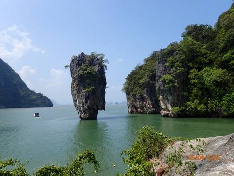       Iconic limestone stack James Bond Island rising out of emerald green water
  