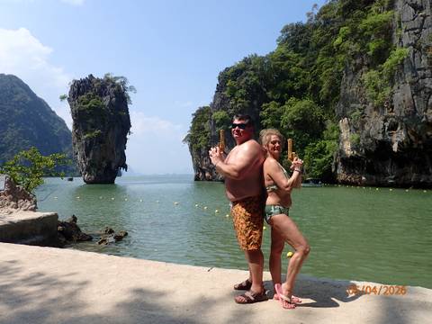       Couple striking James Bond pose in swimsuits with limestone island backdrop
  