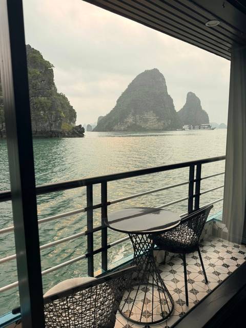       Balcony view over emerald karst islands of Halong Bay with cruise ships in distance
  