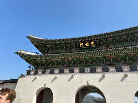       Detailed view of the ornate roofline and signboard of Gwanghwamun Gate under clear sky.
  