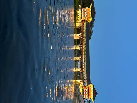       Illuminated covered bridge reflecting on calm water at blue hour.
  