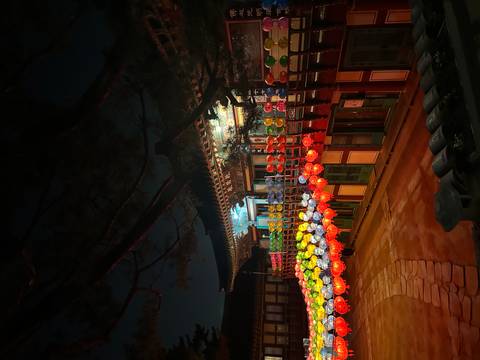       Traditional Korean building decorated with colorful lanterns glowing at night.
  