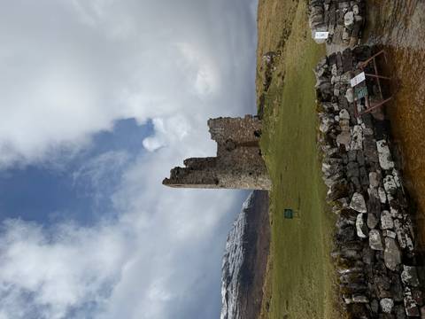       Ruins of Ardvreck Castle against backdrop of snowy hills and moody sky.
  