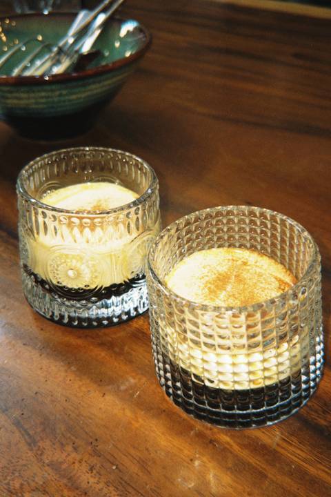       Close-up of two vintage glasses filled with creamy Vietnamese egg coffee on a wooden table.
  