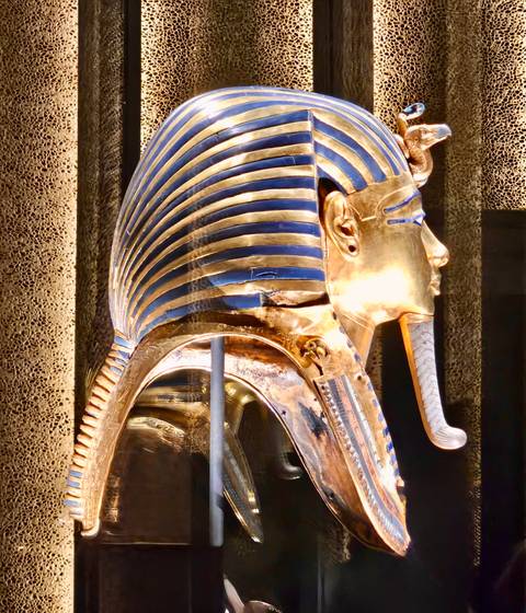       Close-up of Tutankhamun’s gilded death mask gleaming under museum lights.
  