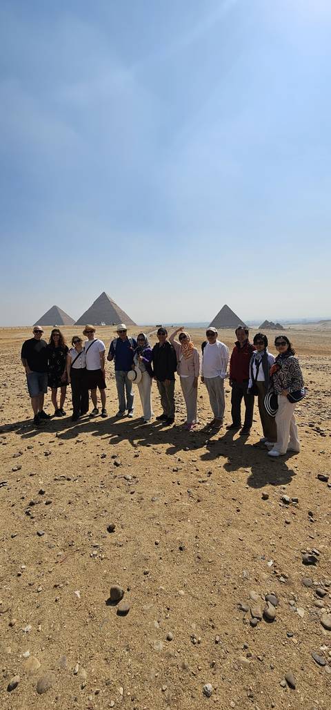       A tour group poses before the three iconic pyramids rising from the Giza Plateau.
  