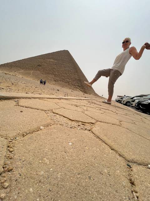       Playful forced-perspective shot of a visitor 'kicking' the Bent Pyramid on a hazy day.
  