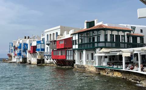       Colorful waterfront houses of Mykonos’ Little Venice line calm Aegean waters.
  