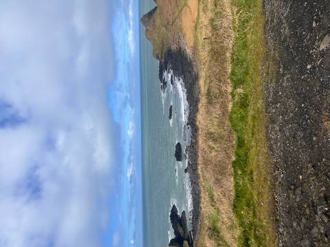       Rocky northern Irish coastline with breaking waves under a mix of blue sky and clouds.
  