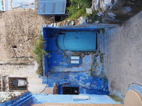       Vibrant blue painted doorway and weathered wall in a narrow alley of the medina.
  
