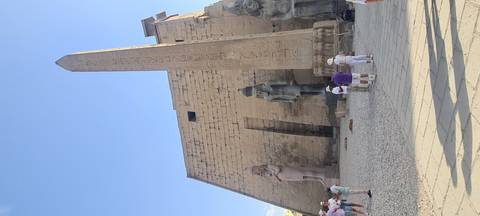       Obelisk and colossal statues at Luxor Temple courtyard with tourists exploring
  