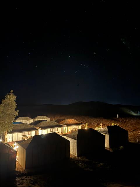       Luxury desert camp tents glow under a star-filled night sky, silent dunes surrounding the scene.
  