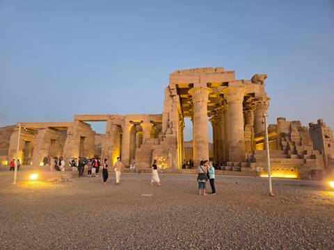       Soft dusk light on the monumental columns of Kom Ombo Temple while visitors explore the illuminated site.
  