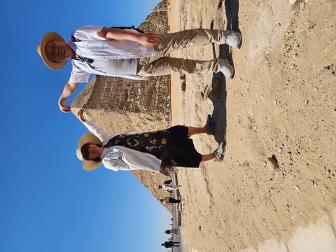       Travellers mimic touching the Bent Pyramid in Egypt’s desert landscape.
  