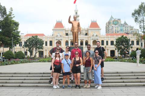       Tour group poses on the steps before the bronze Ho Chi Minh statue and French-colonial City Hall façade in Ho Chi Minh City.
  