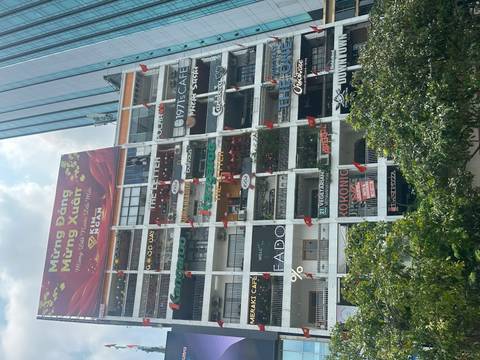      High-rise apartment block in Ho Chi Minh City covered in colourful café signs and flags.
  