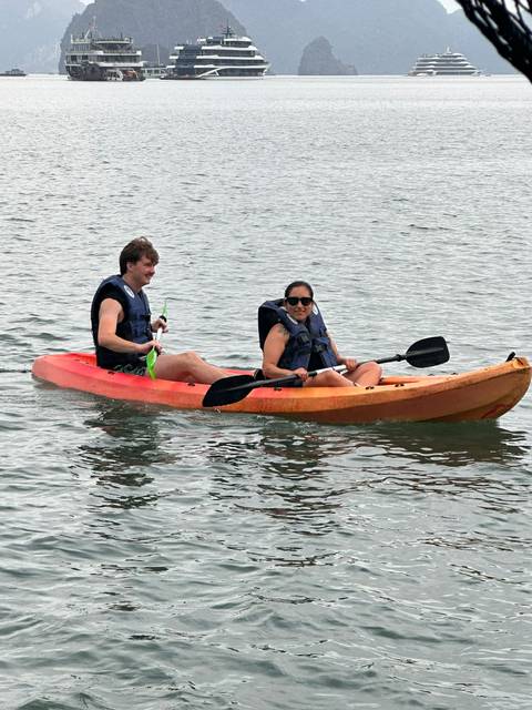       Close-up of two kayakers smiling while paddling on calm water.
  