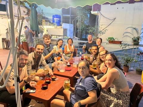       Travelers sit around low tables enjoying drinks at a casual Vietnamese eatery.
  