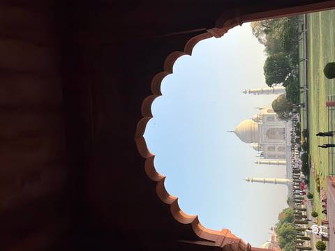       The Taj Mahal framed by a scalloped sandstone archway in soft morning light.
  