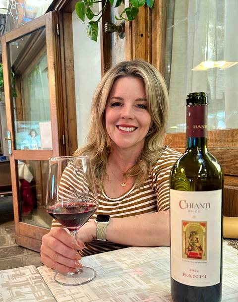       Woman enjoying a glass of Chianti wine inside a cozy Italian restaurant
  
