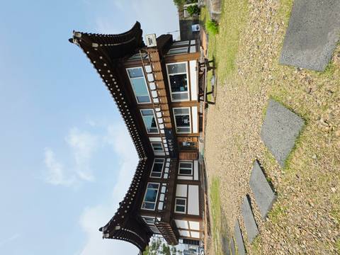       Traditional Korean hanok-style building forming a courtyard under a clear blue sky with a picnic bench in the foreground.
  