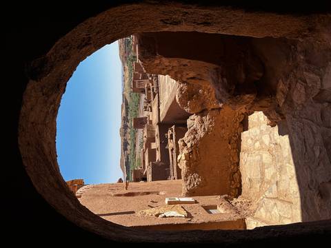       Sun-lit view through a stone arch over the earthen ksar of Ait Benhaddou
  