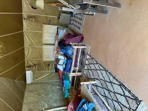       Inside a desert camp tent with unmade twin beds and scattered suitcases
  